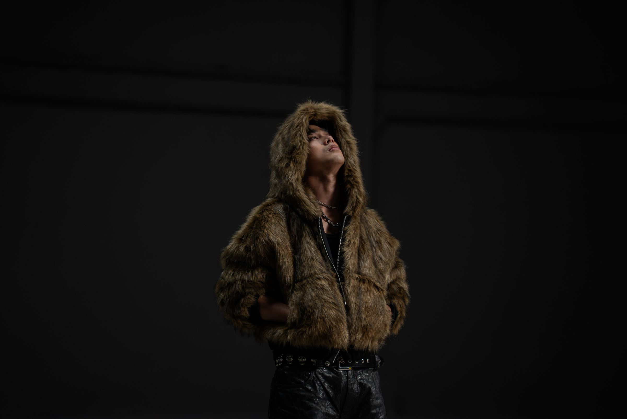 Josh Cullen in a fur hood, head tilted back, in a dark room